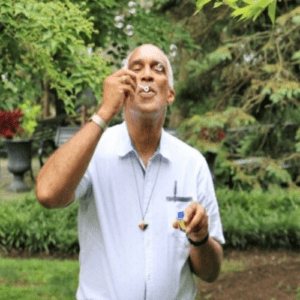 A man in white shirt holding cigarette and smoking.