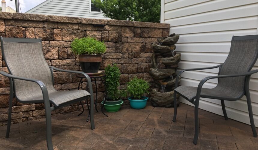 A patio with chairs and potted plants on the side.