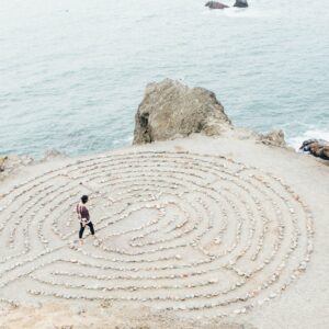 A person walking on top of a sand labyrinth.
