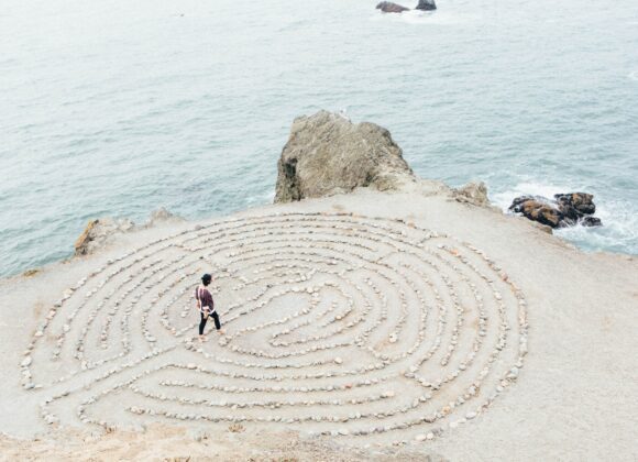 A person walking on top of a sand labyrinth.