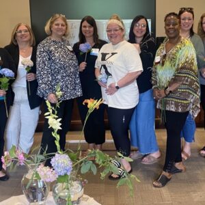 Group of women holding flowers smiling.