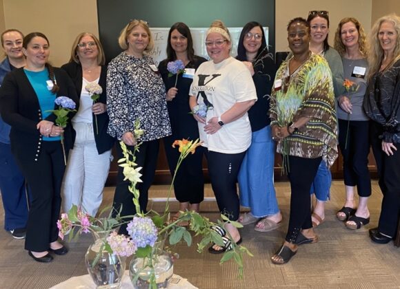 Group of women holding flowers smiling.