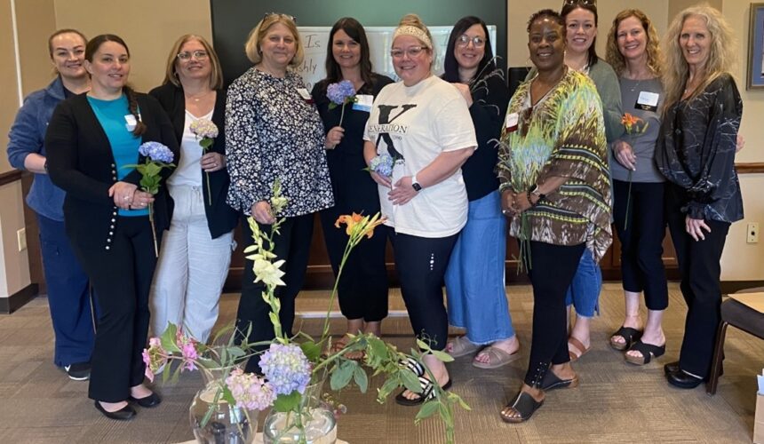 Group of women holding flowers smiling.