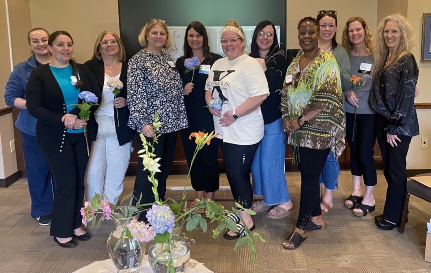 Group of women holding flowers smiling.