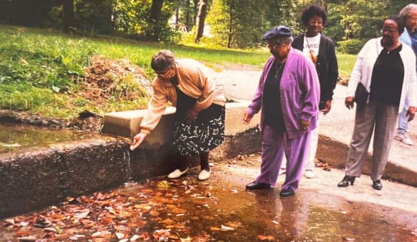 An original hosted group at Cranaleith in the late 1990s trying to catch water from a spring in their hands.