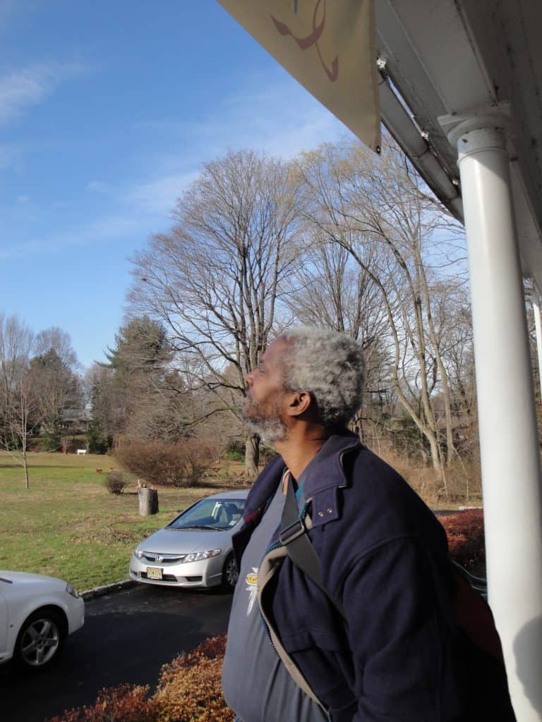 Man standing outside the historic house looking at the sky.