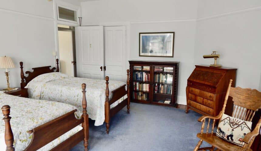 An overnight accommodation with double beds and a wooden bookcase.