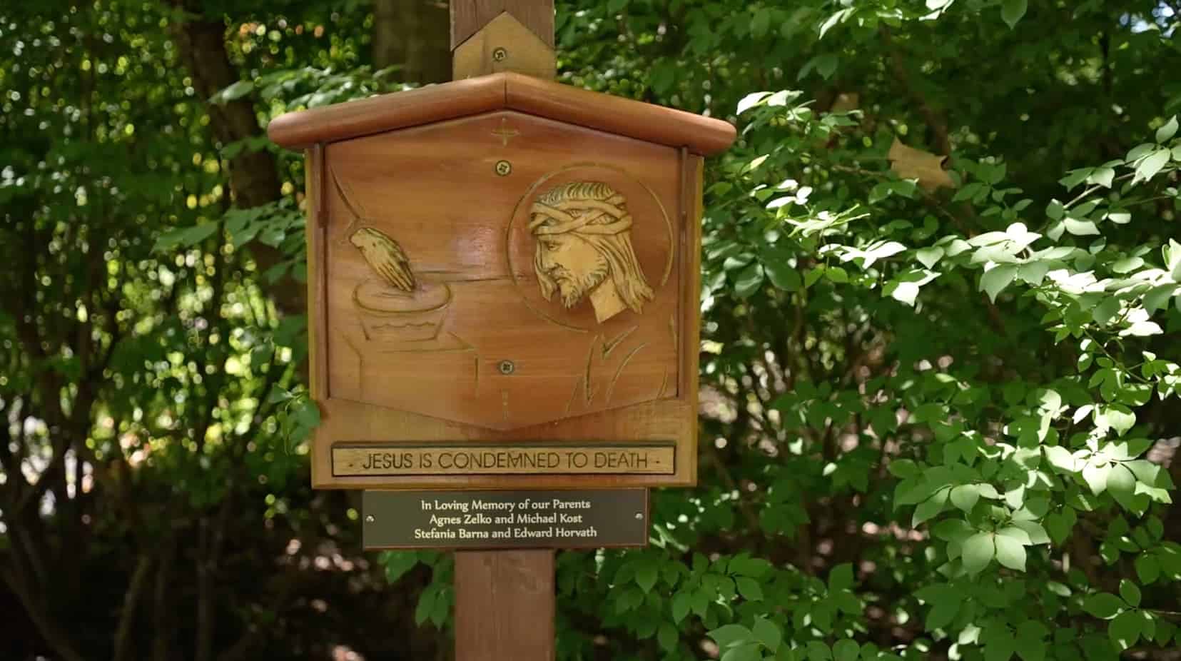 A wooden Jesus sign with a plaque reading "Jesus is Condemned to Death"