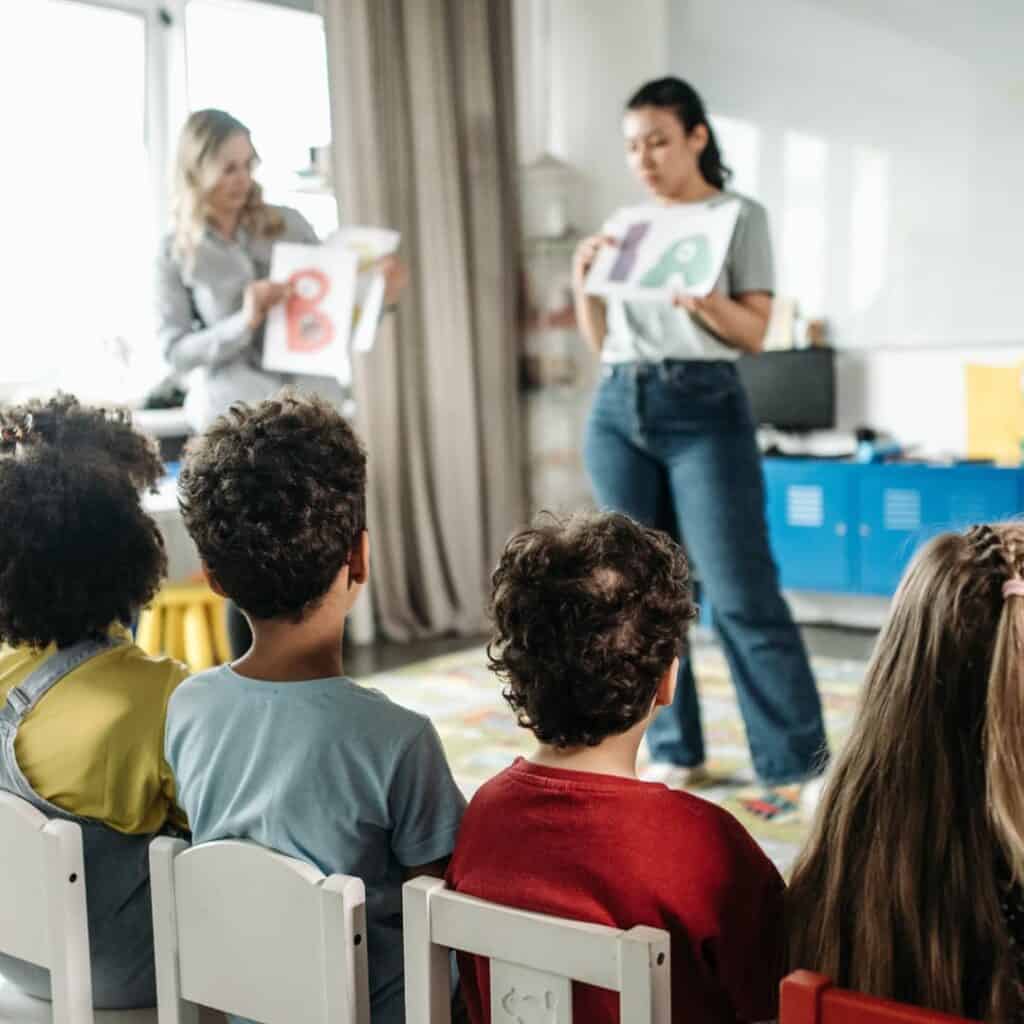 Two teachers visually teaching children letters with art.