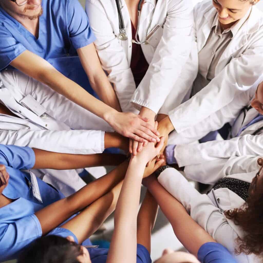 Healthcare workers in a huddle with hands on top of each other.