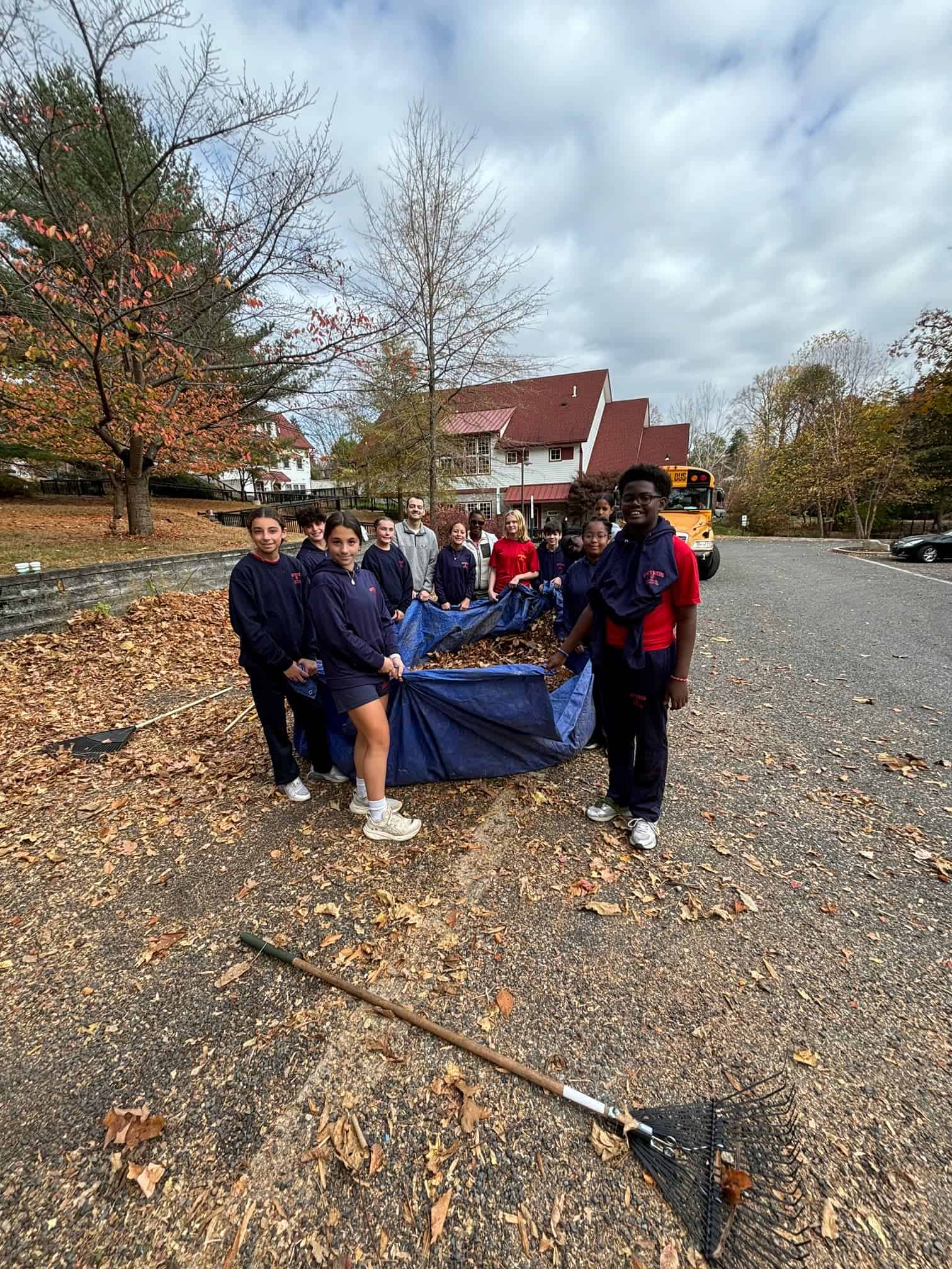 Gwynedd Mercy Academy Elementary holding a large tarp full of leaves in the parking lot.