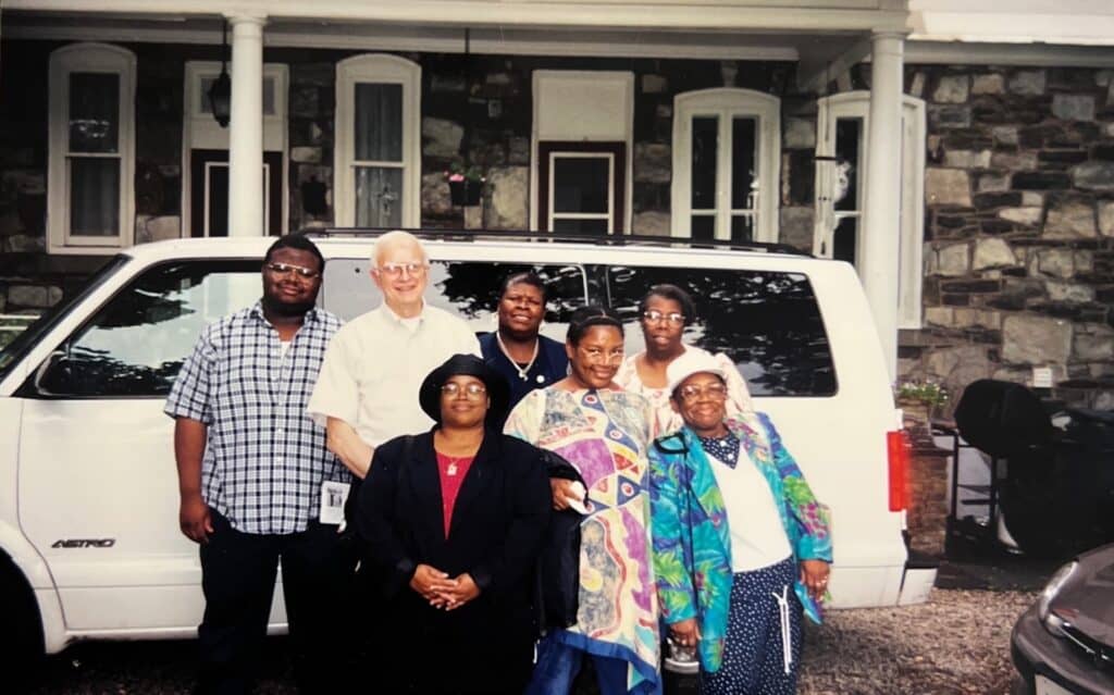 Vintage photo of a group posing for a photo in front of a truck outside of the Historic House.