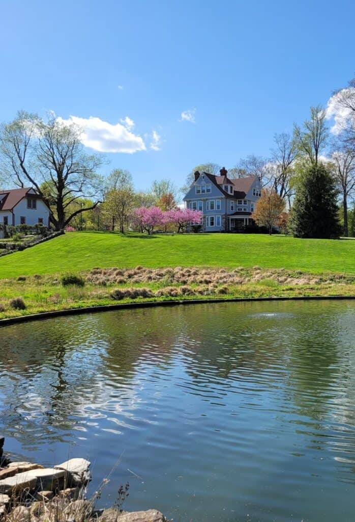 Photo of Cranaleith's pond with the historic house, administration building, and trees in the background.