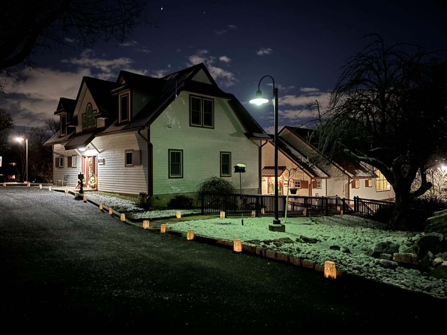 Cranaleith's Administration Building and Education & Conference Center at night with luminaries lit up on the ground outside.