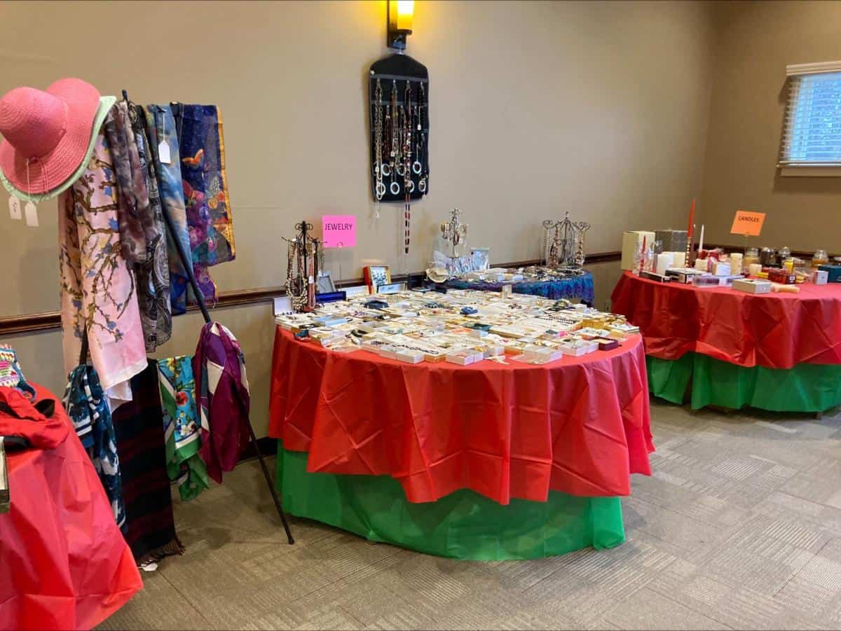 Cranaleith Holiday Sale round tables decorated with red table cloths, selling jewelry and candles.