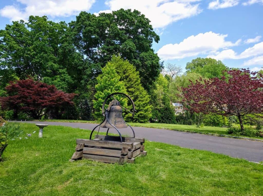 Cranaleith bell with driveway and multi-colored trees in the background.