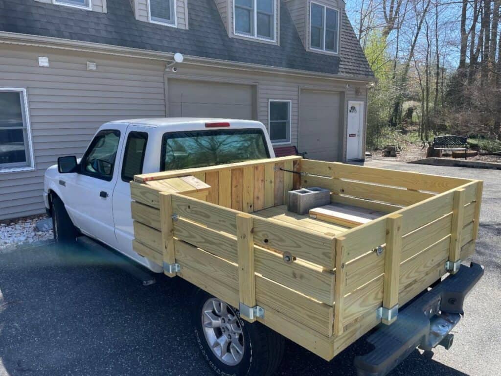 A newly finished wooden truck bed on a white truck.