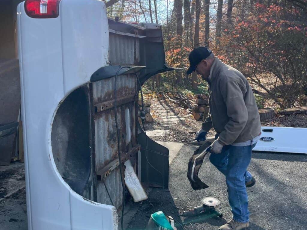 A man prepping a worn down truck bed to be replaced.